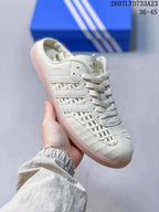 Close-up side view of an off-white adidas Samba OG mule-style sneaker with woven detailing and a translucent gum-colored outsole.
