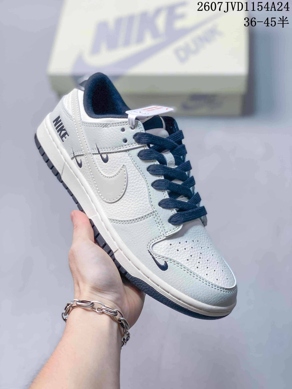 Angled side view of the white and navy Nike sneaker showing the layered side Swoosh, heel branding and low-top silhouette.