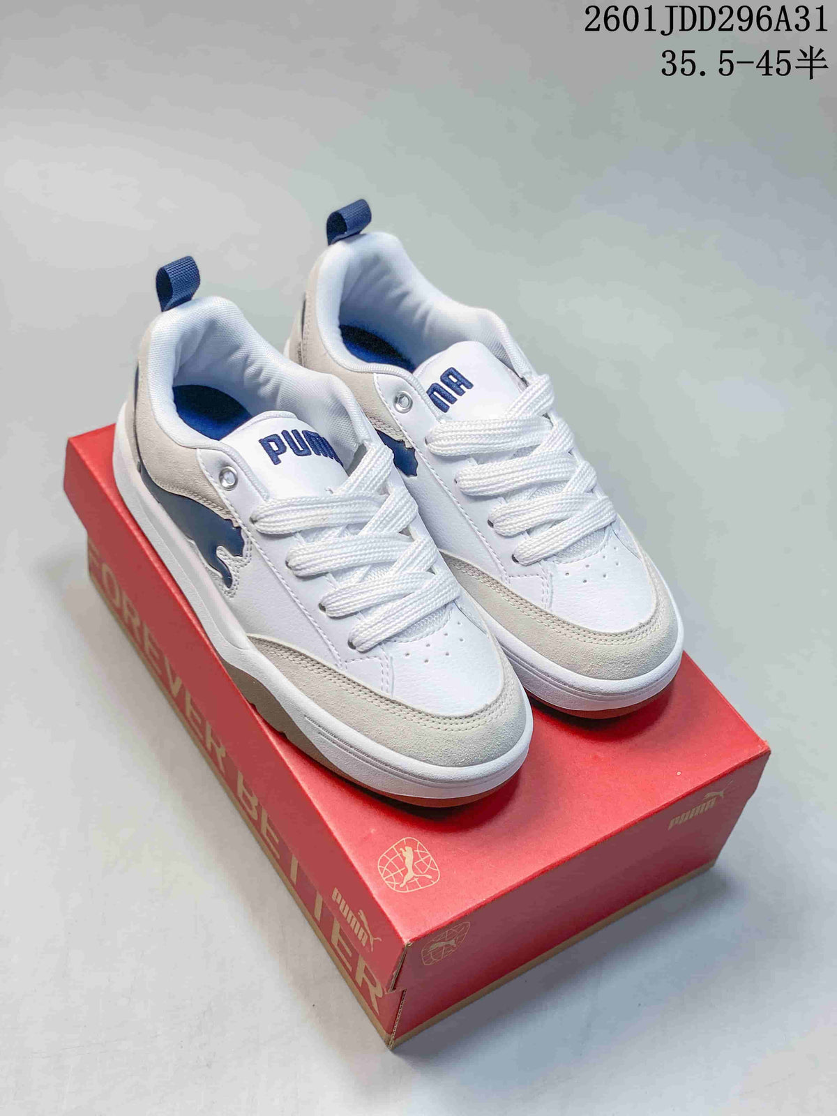 Pair of white PUMA sneakers with blue accents displayed on a red shoebox.
