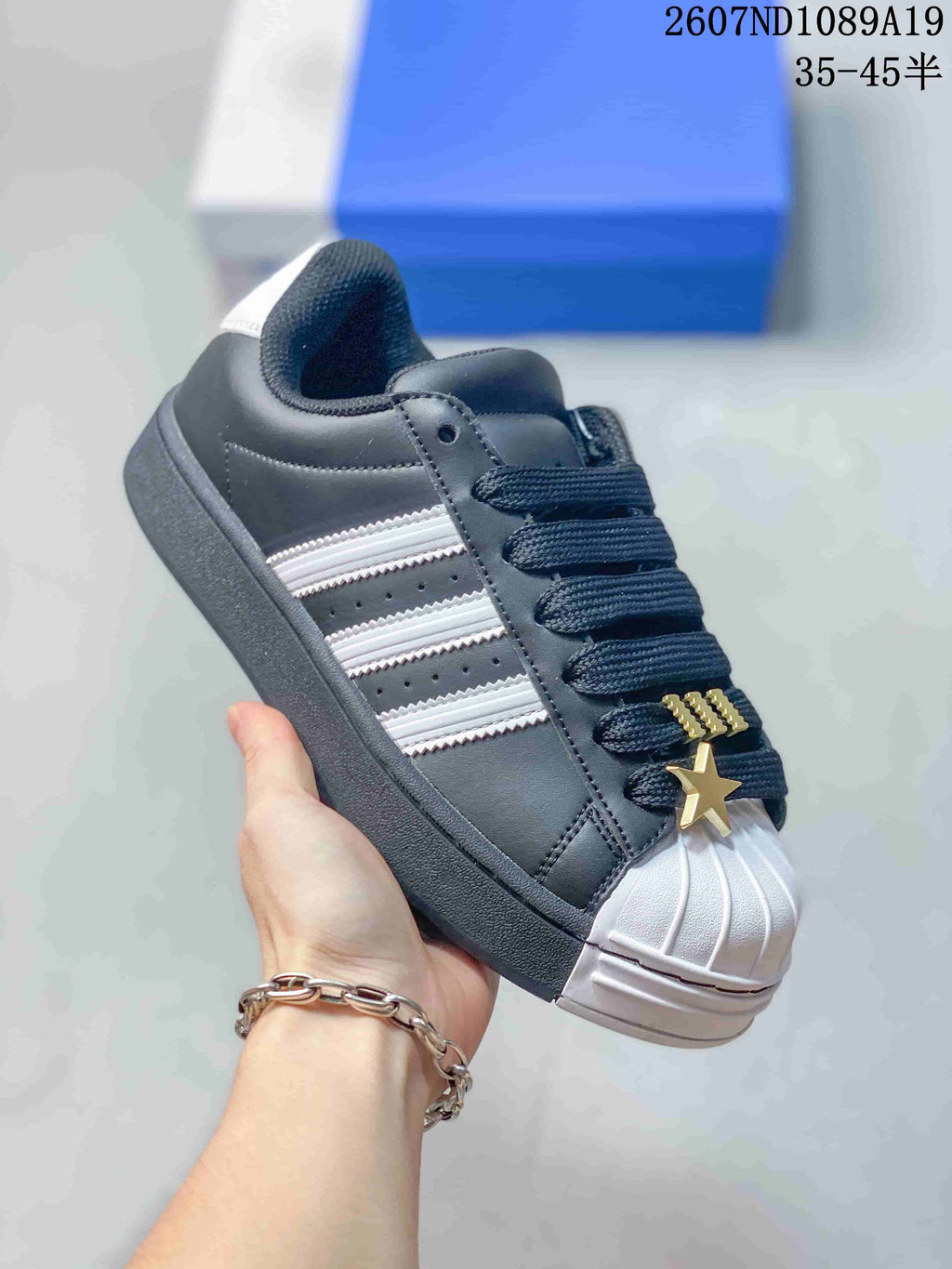 Angled side view of the black and white sneaker showing the shell toe, white stripes and decorative gold-tone star.