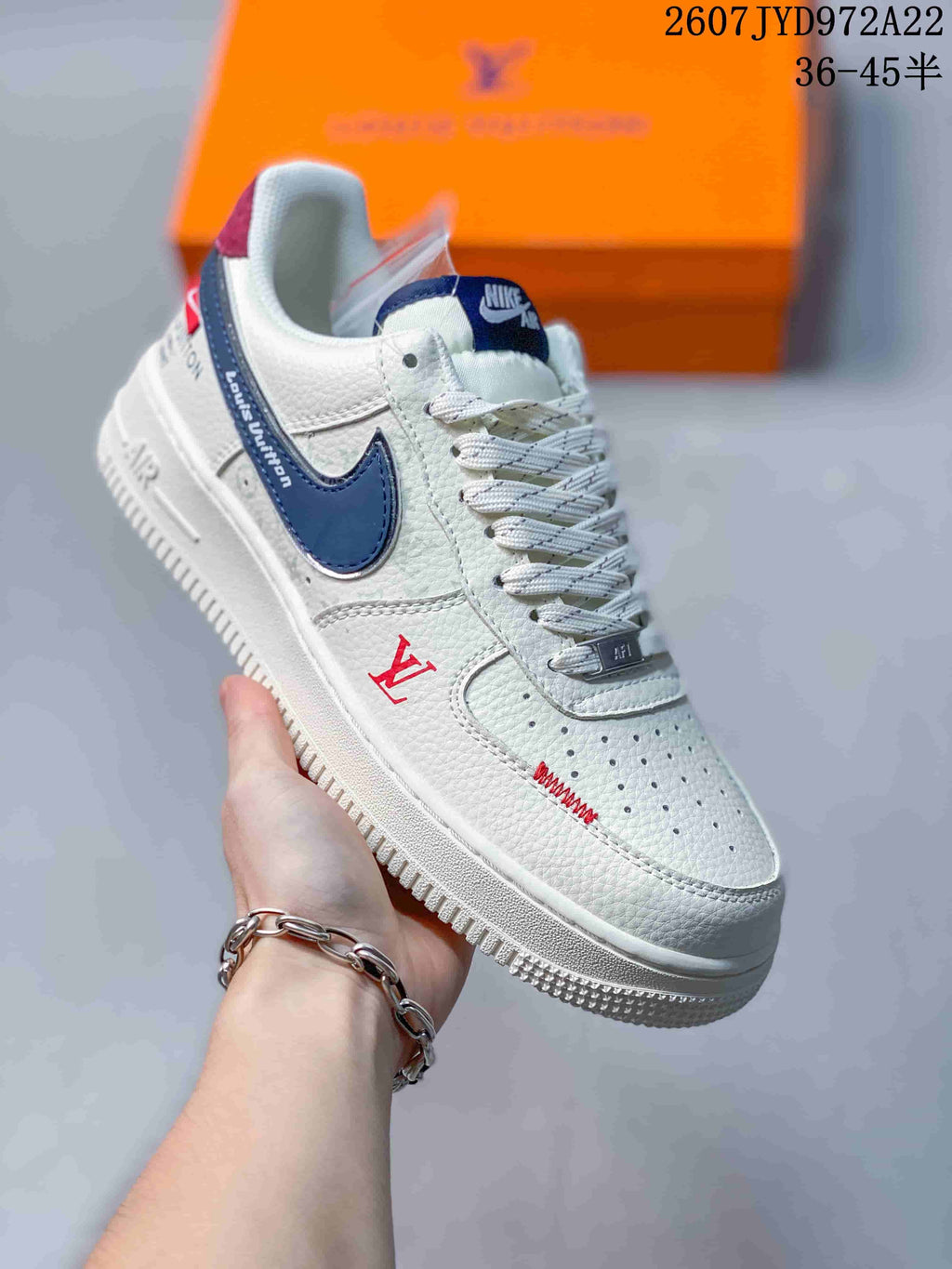 Angled close view of the white sneaker showing navy side accents, red detailing, perforated toe box, and visible Louis Vuitton reference graphics.