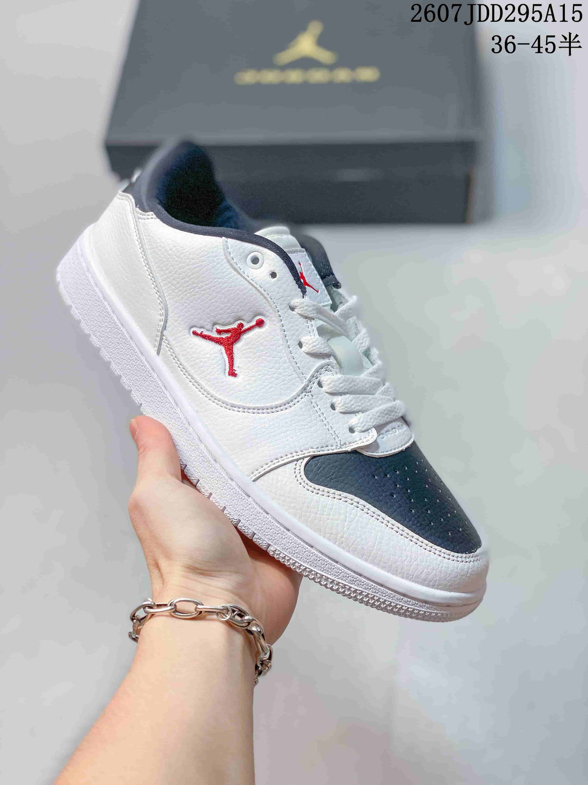 White and dark grey low-top Jordan sneaker held at an angle, with a dark toe panel and red side-panel logo.