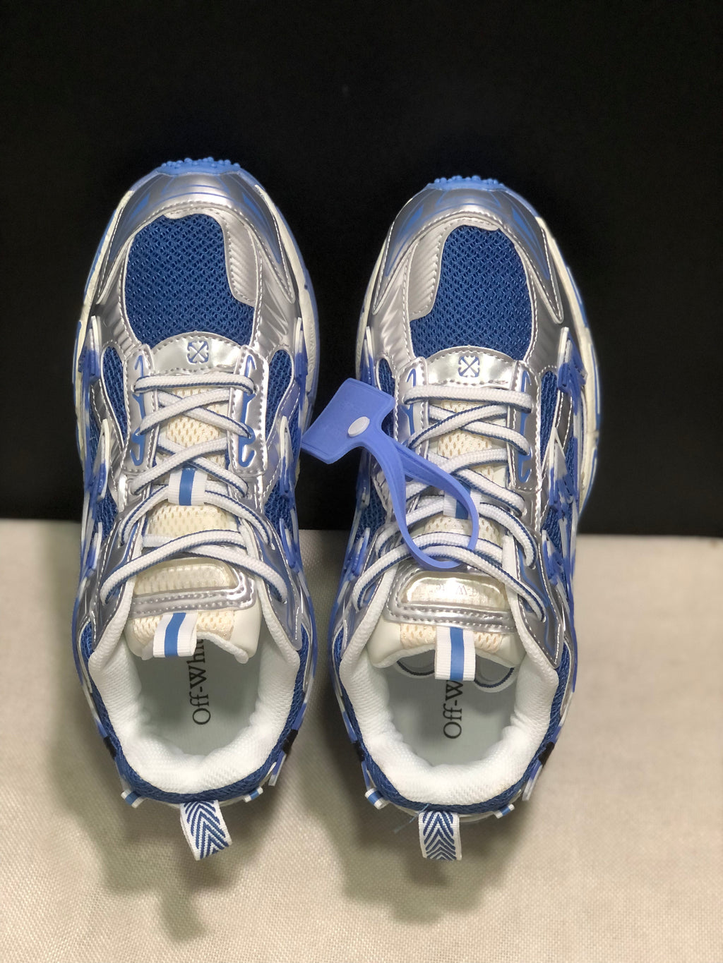 Top-down view showing the blue mesh sections, silver overlays, white laces, and branded insoles.