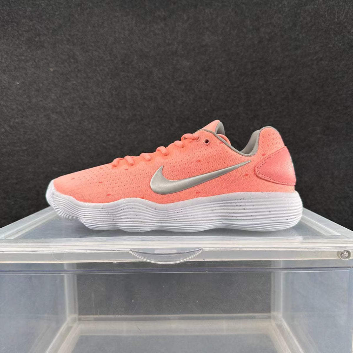 Side view of a pink Nike low-top sneaker with a silver-tone Swoosh and white ridged sole.