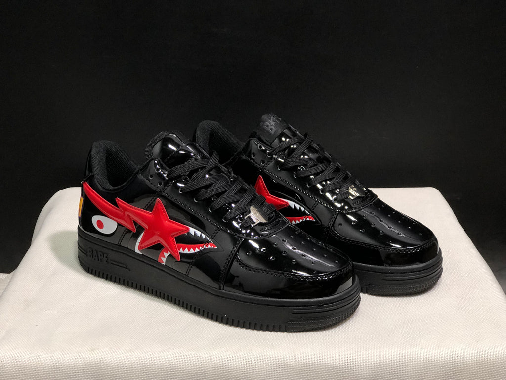Three-quarter front view highlighting the glossy black finish, red star overlay, shark graphics, and metal lace details.