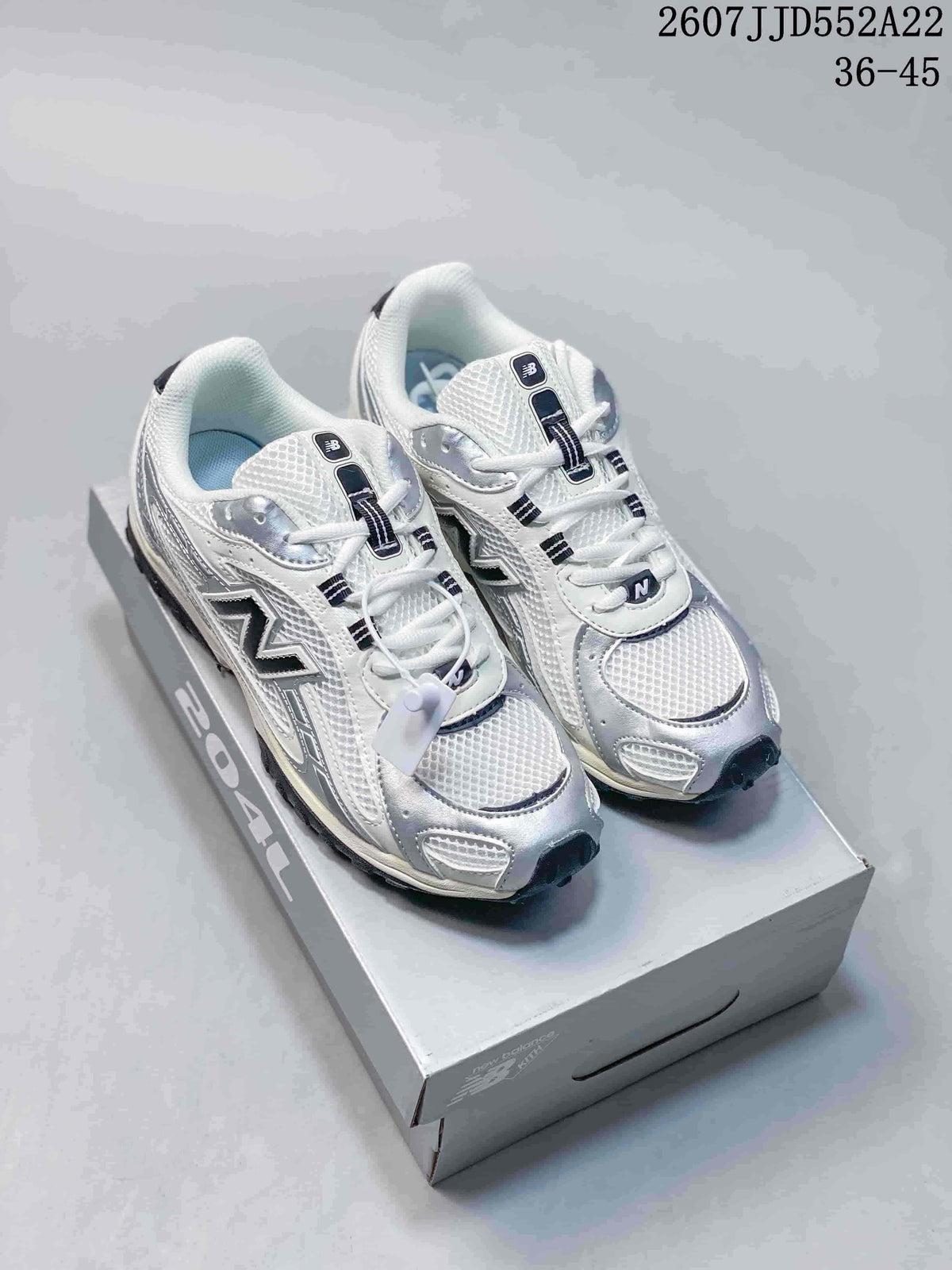 Pair of white and silver New Balance NB204 sneakers displayed on a shoebox; the image shows the printed range 36-45 and code 2607JJD552A22.
