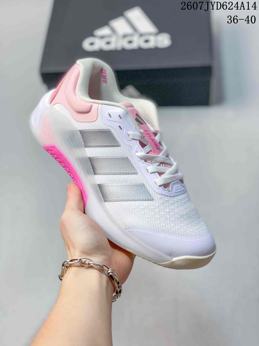 White adidas Dropset 4 training shoe with pink accents, shown from a front three-quarter angle beside an adidas box.