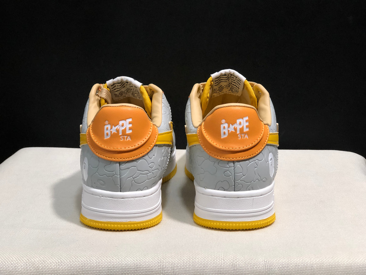 Rear view showing orange heel panels, BAPE STA branding, and grey embossed heel sections.