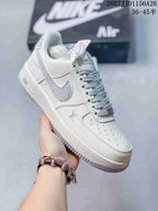 Angled side view showing the white upper, grey swoosh-style detail, printed heel text and textured outsole.