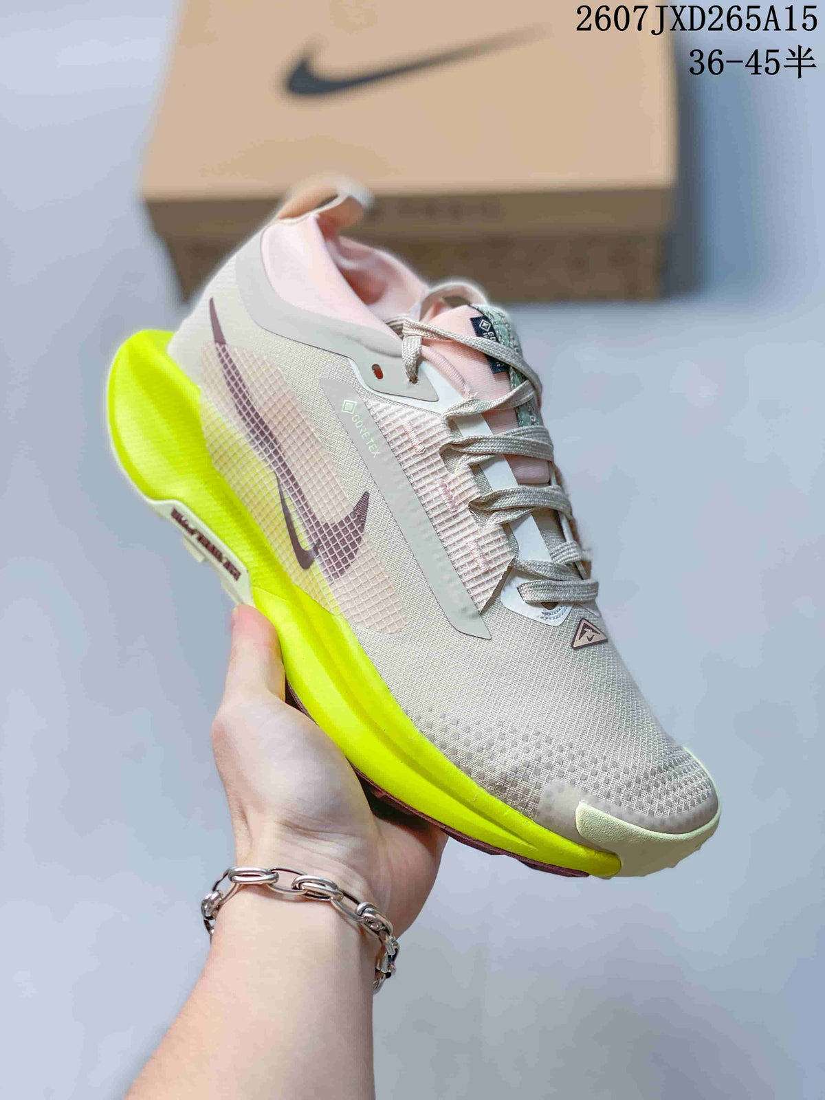 Angled side view of the Nike Pegasus Trail 5 sneaker showing the light gray upper, pink accents, Nike swoosh, and neon yellow midsole.