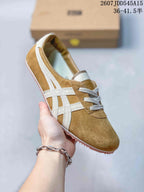 Tan suede-style low-top sneaker with white side stripes, gray laces, and a tan textured outsole.