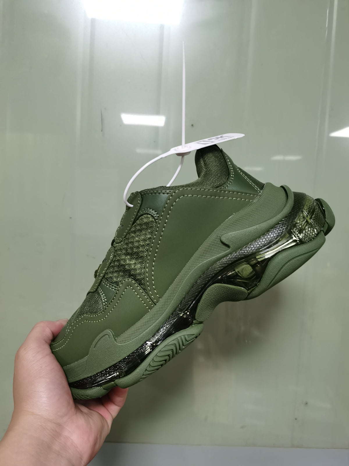 Rear-side view of an army green Balenciaga Triple S sneaker showing the layered upper, heel structure and clear sole details.