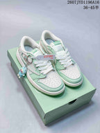 Pair of mint green and white Jordan low-top sneakers on a matching green box, with Labubu-themed details and a blue character charm.