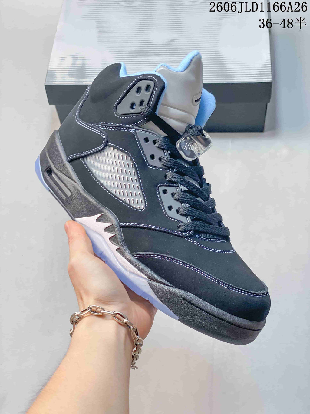 Angled side view of a dark high-top sneaker with mesh panels, light blue details, and a translucent outsole.