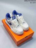 Pair of white and blue low-top sneakers shown from the front on an orange box