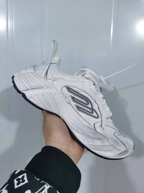 Side view of white lace-up sneakers with grey layered detailing and a black outsole.