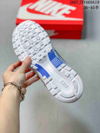 Close-up of the patterned white outsole with blue accent sections, held above a red Nike shoebox.