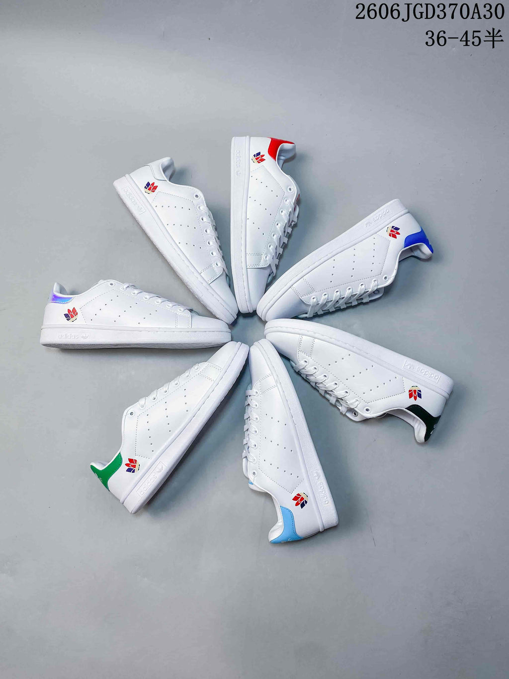 Several white Stan Smith-style sneakers arranged in a circle, showing different heel-tab colors.