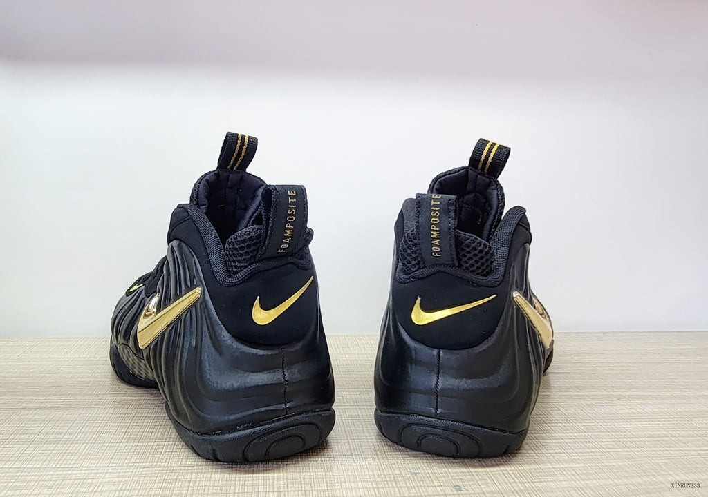 Rear view of black Nike Air Foamposite Pro sneakers with metallic gold accents