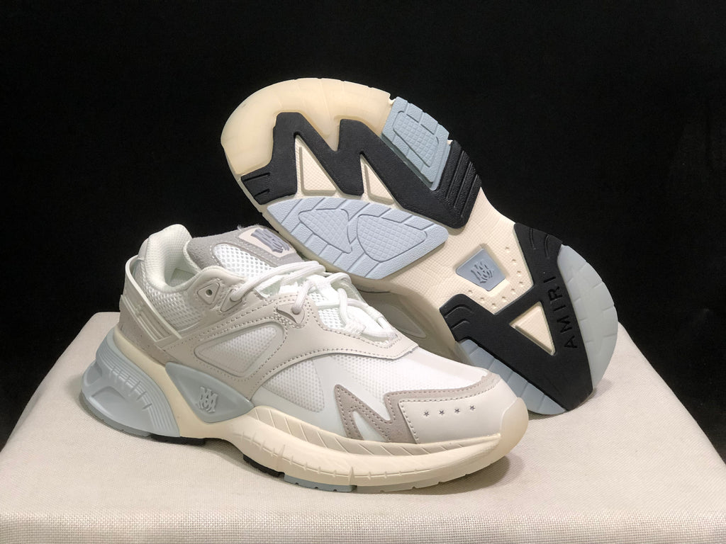 AMIRI MA Runner sneakers shown from the side with one shoe lifted to reveal the contrast outsole.