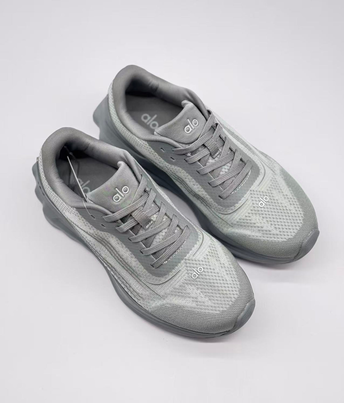 Top view of a pair of gray Alo Runner sneakers showing the lace arrangement, padded collars, and textured uppers.