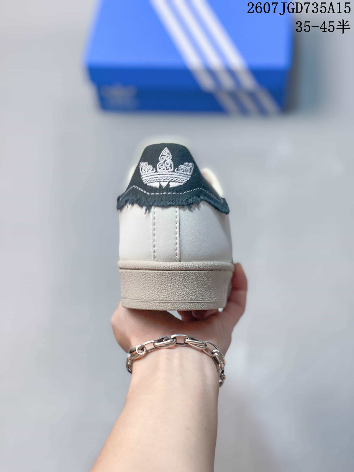 Rear view of the sneaker showing the white heel, black heel tab, and embroidered Trefoil-style detail.