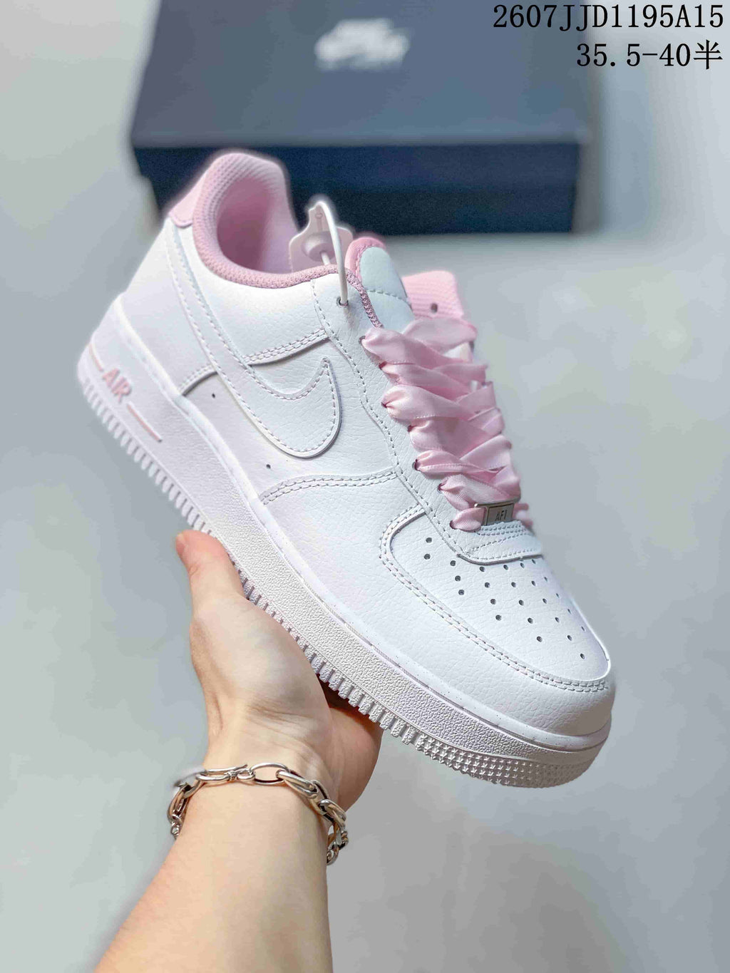 Angled side view of a white Nike Air Force 1 low-top sneaker with pink laces, pink collar lining, stitched Swoosh, and white outsole.