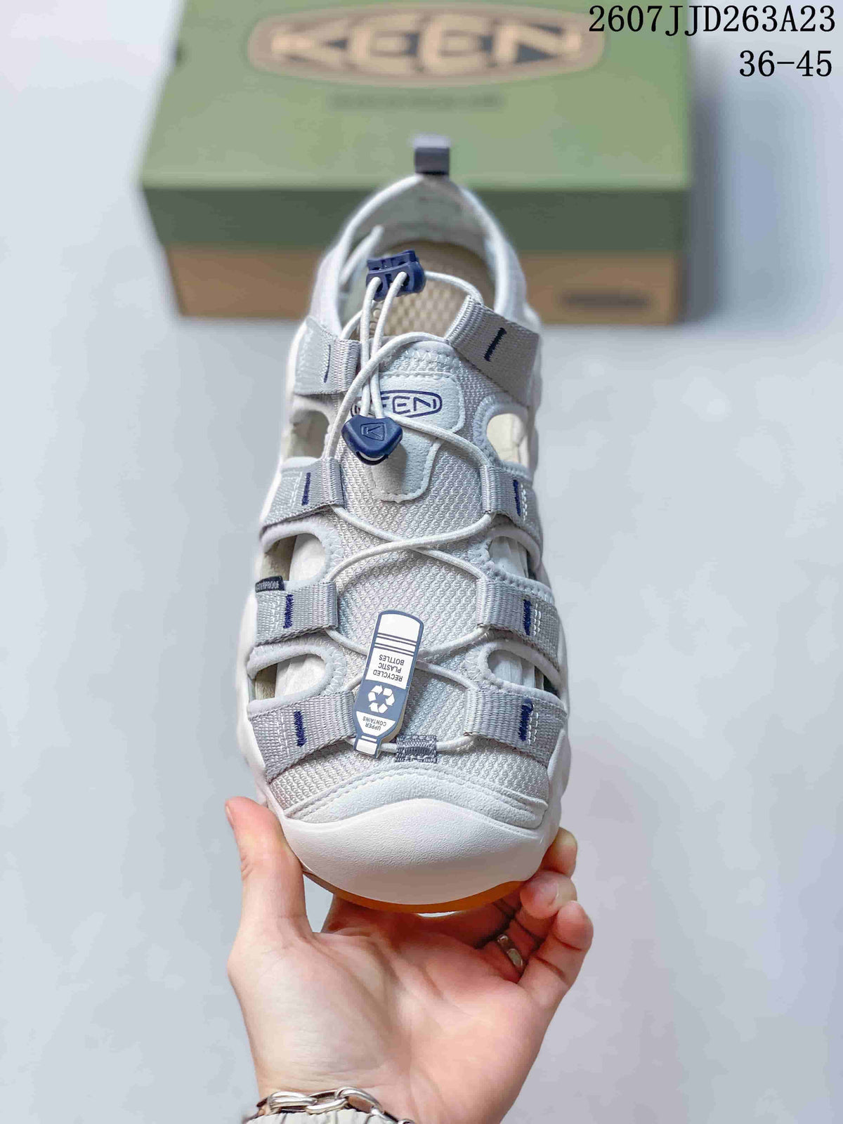 Front view showing the gray webbing, open panels, and blue lace toggle.
