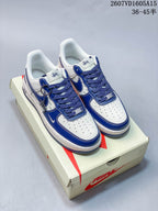 Pair of white and blue low-top sneakers with blue overlays, patterned side panels, blue laces, and decorative hanging charms.