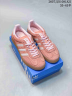Pair of pink and white adidas Gazelle sneakers displayed on a blue shoe box.