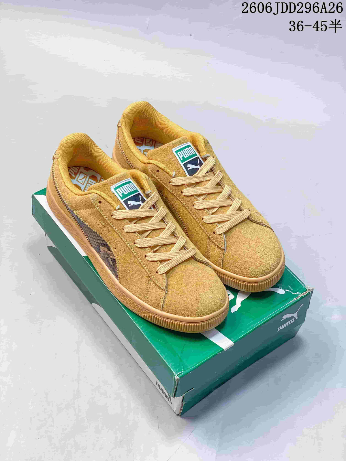 Pair of wheat PUMA low-top sneakers displayed on a green PUMA shoebox, with the side formstrip and branded tongue labels visible.