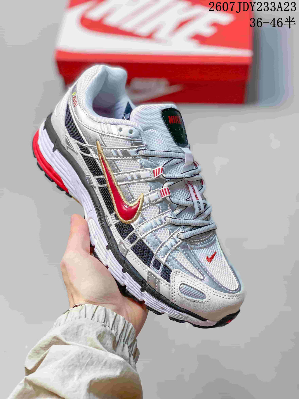 Side view of a white and silver Nike P-6000 sneaker with red Swoosh detailing, layered panels, mesh sections, and a textured outsole; the image shows style code 2607JDY233A23 and size range 36–46.