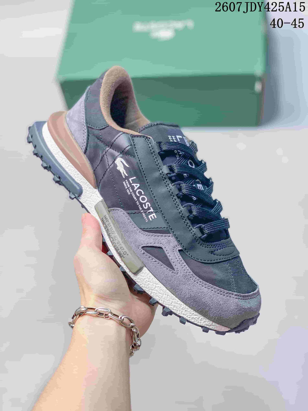 Side view of a black and gray Lacoste sneaker showing layered panels, branding and a rugged outsole.