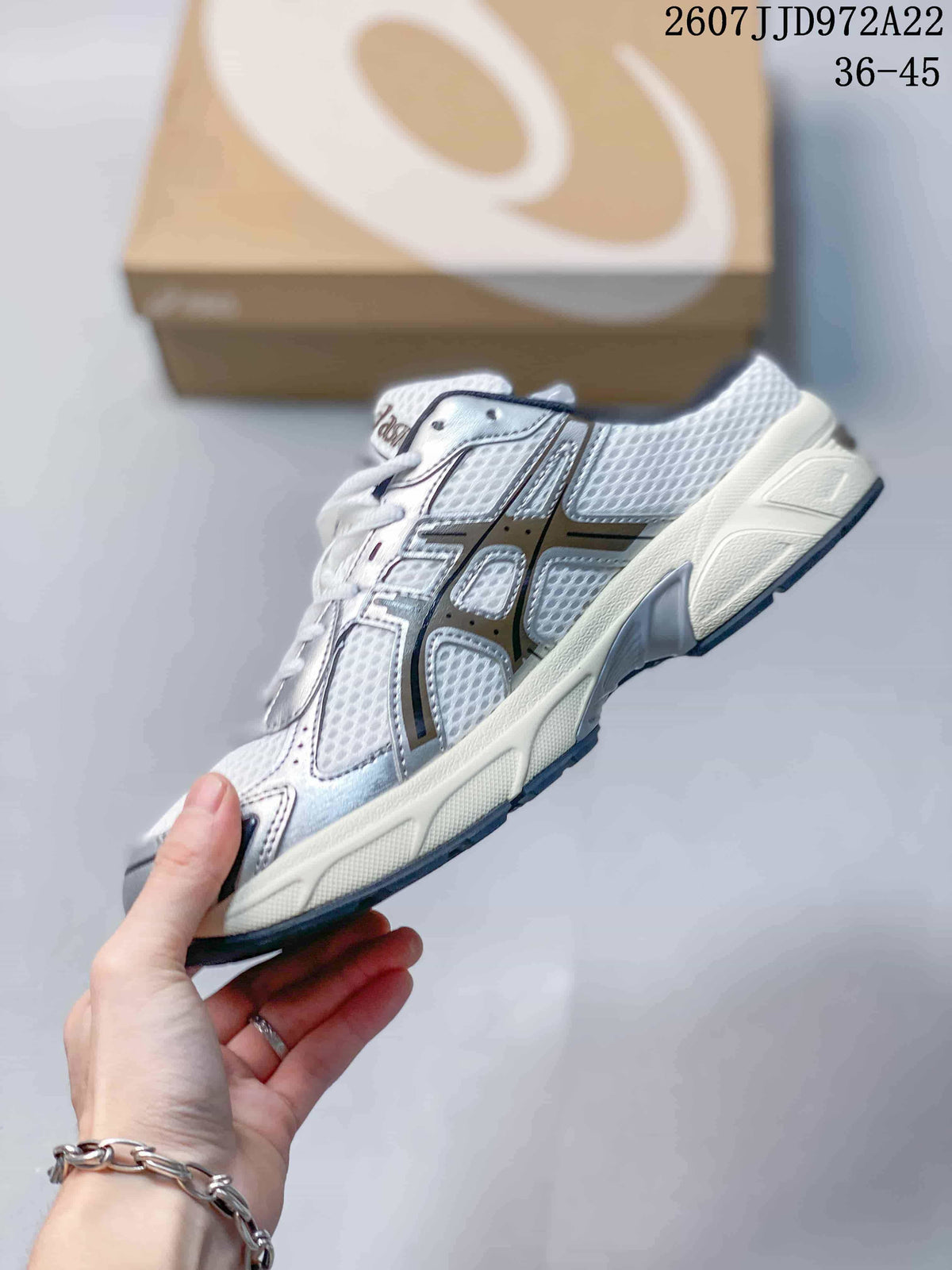 Side view of the white and silver sneaker highlighting mesh panels, layered overlays, lace-up construction, and the textured outsole; image text shows style code JJD972A22 and size range 36–45.