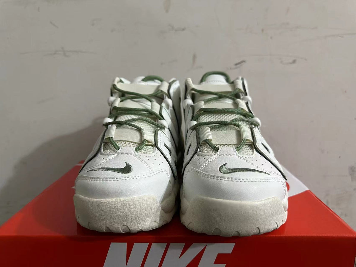 Front view of white Nike sneakers with green laces and small toe logos