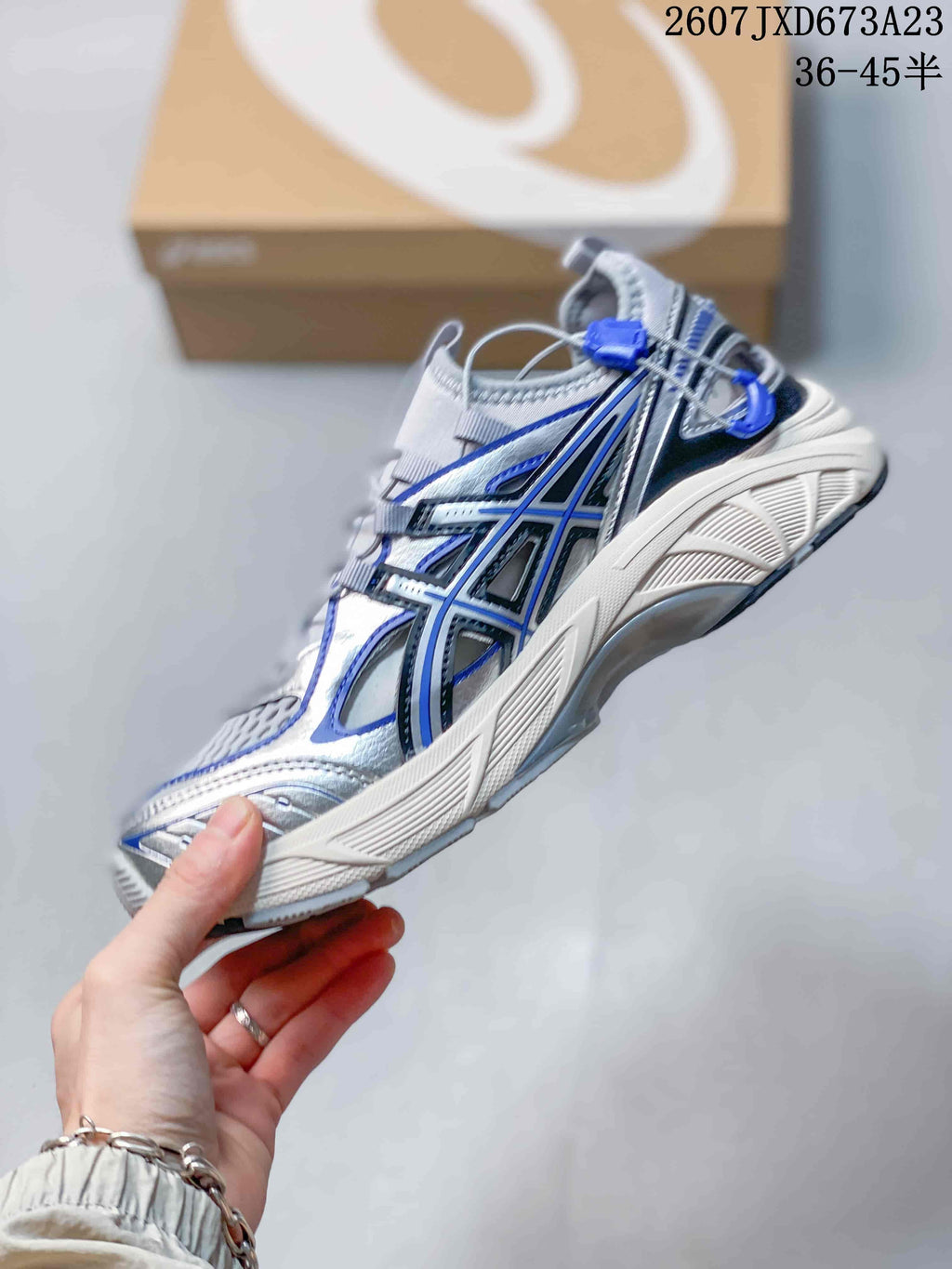 Side view of the sneaker showing layered ASICS branding, blue accents, mesh panels, and the sculpted midsole.