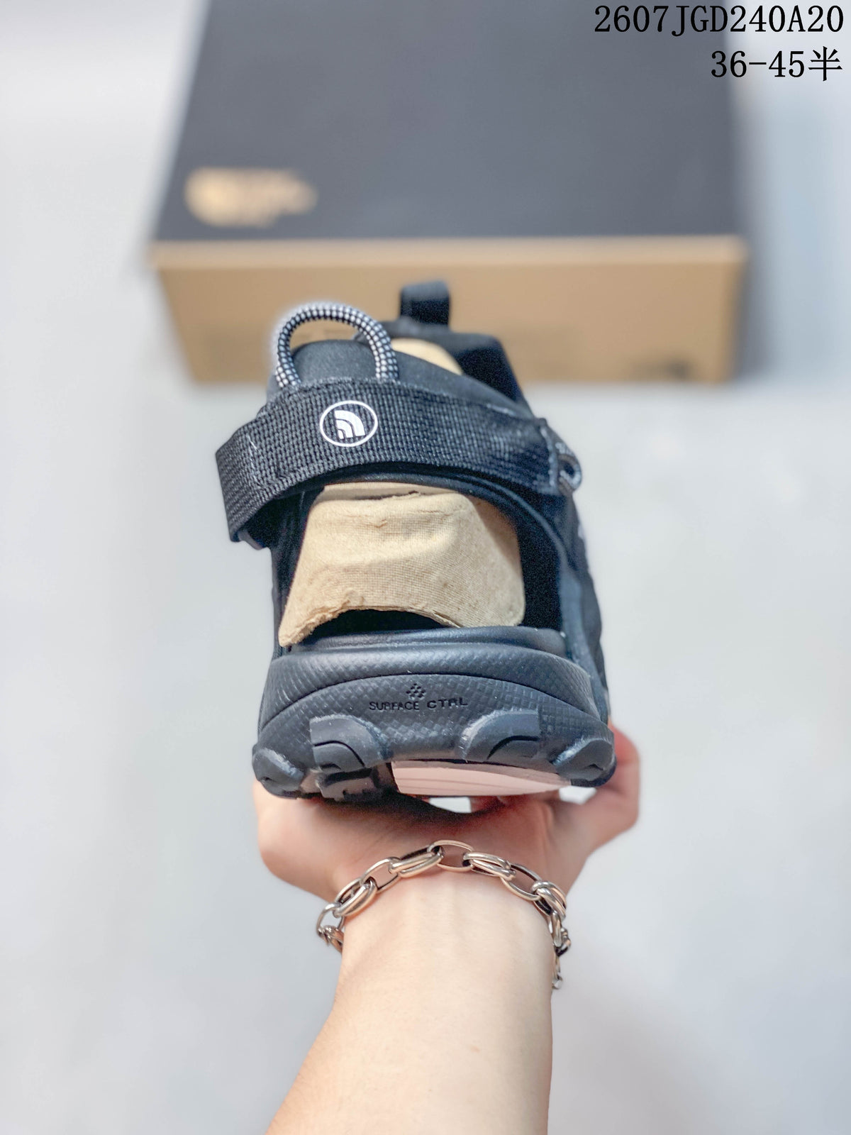 Rear view of a black sandal showing the heel strap, open heel area, textured outsole, and visible branding.