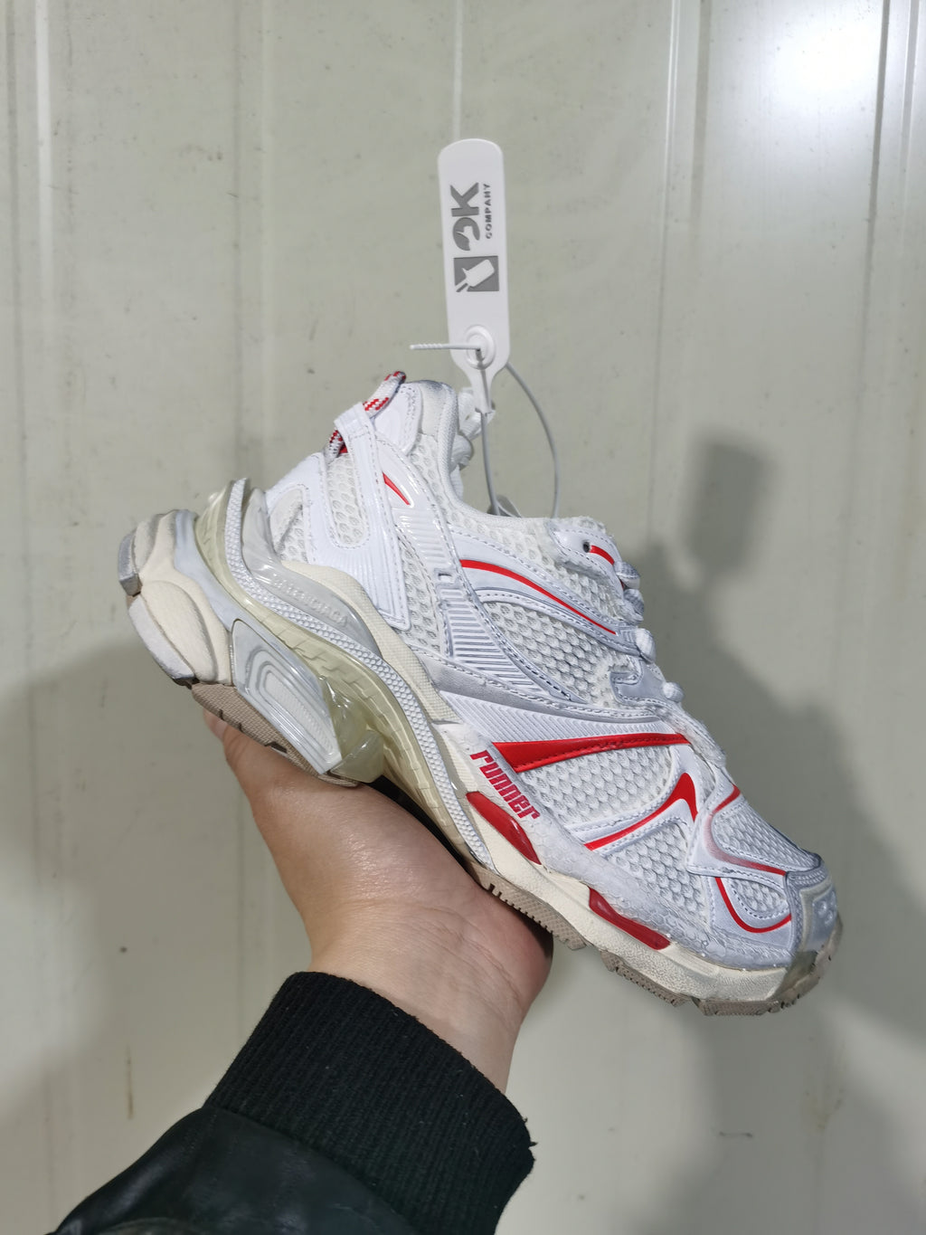 Angled close-up of the white Puma 9260 Runner 2 sneaker showing layered panels, mesh-textured sections, and red accents.