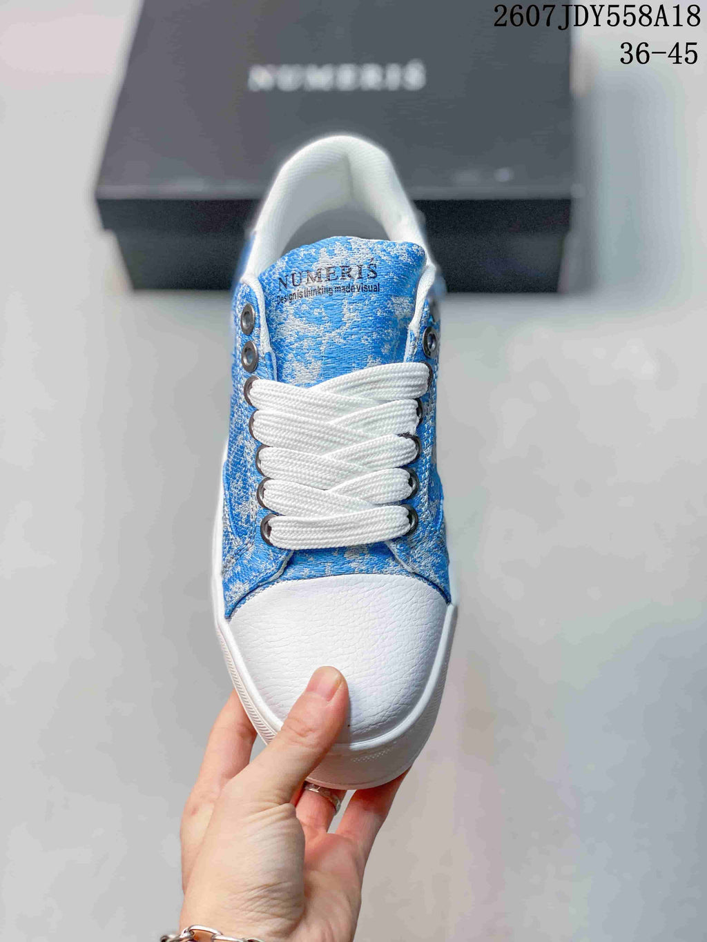 Top view of the sneaker showing the blue patterned upper, white laces, white toe cap, and NUMERIS tongue branding.