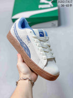 Angled side view of the white PUMA sneaker showing blue side detailing, lace-up closure, and gum-colored outsole.
