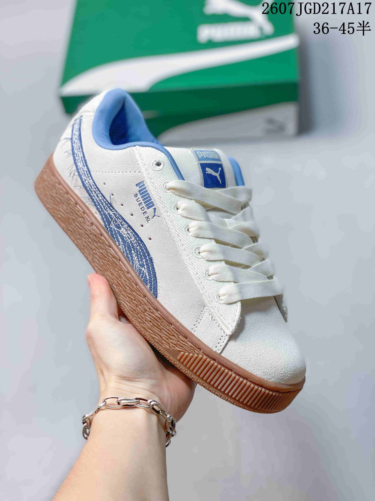 Angled side view of the white PUMA sneaker showing blue side detailing, lace-up closure, and gum-colored outsole.