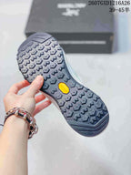 Close view of the dark patterned outsole with a yellow center insert and repeated lug tread.