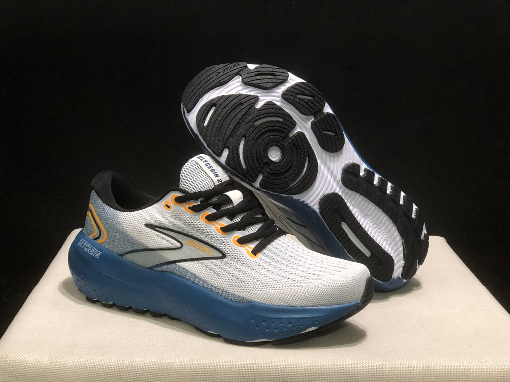 Three-quarter view of the Brooks sneakers with one shoe lifted to reveal the black-and-white outsole pattern.