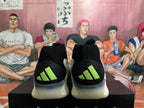 Rear view of black basketball shoes with lime heel logos and white soles