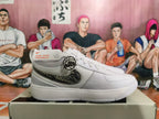 Side view of a white Nike sneaker with a dark patterned Swoosh and ankle strap detail