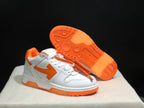 Angled view showing the white upper, orange outsole, textured tread, and attached orange tag.