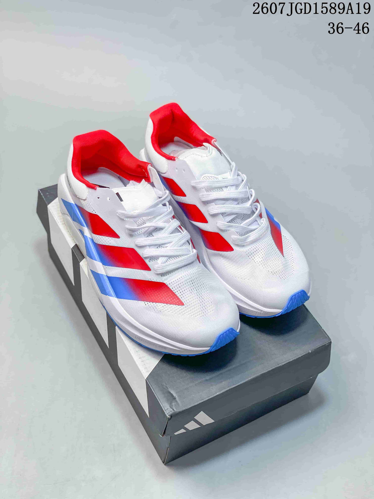 Pair of white adidas Adizero Dropset Pro training sneakers with red and blue details displayed on a shoebox.