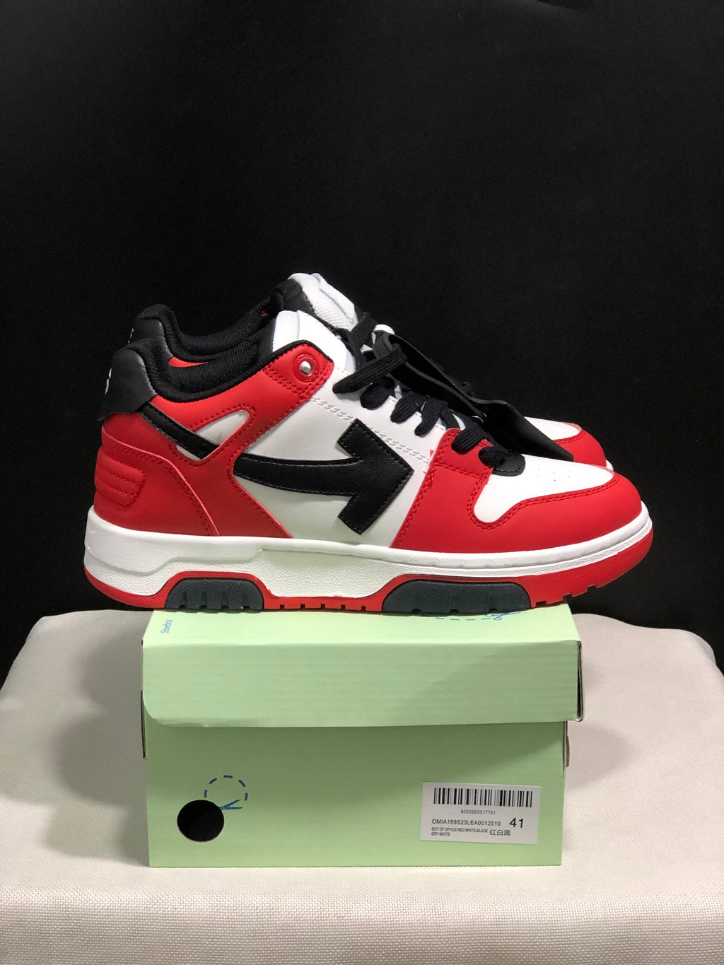 Side view of a red, white, and black low-top sneaker showing the contrasting arrow panel and layered sole.