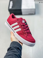 Angled side view of the red adidas sneaker with white stripes and a white rubber sole.