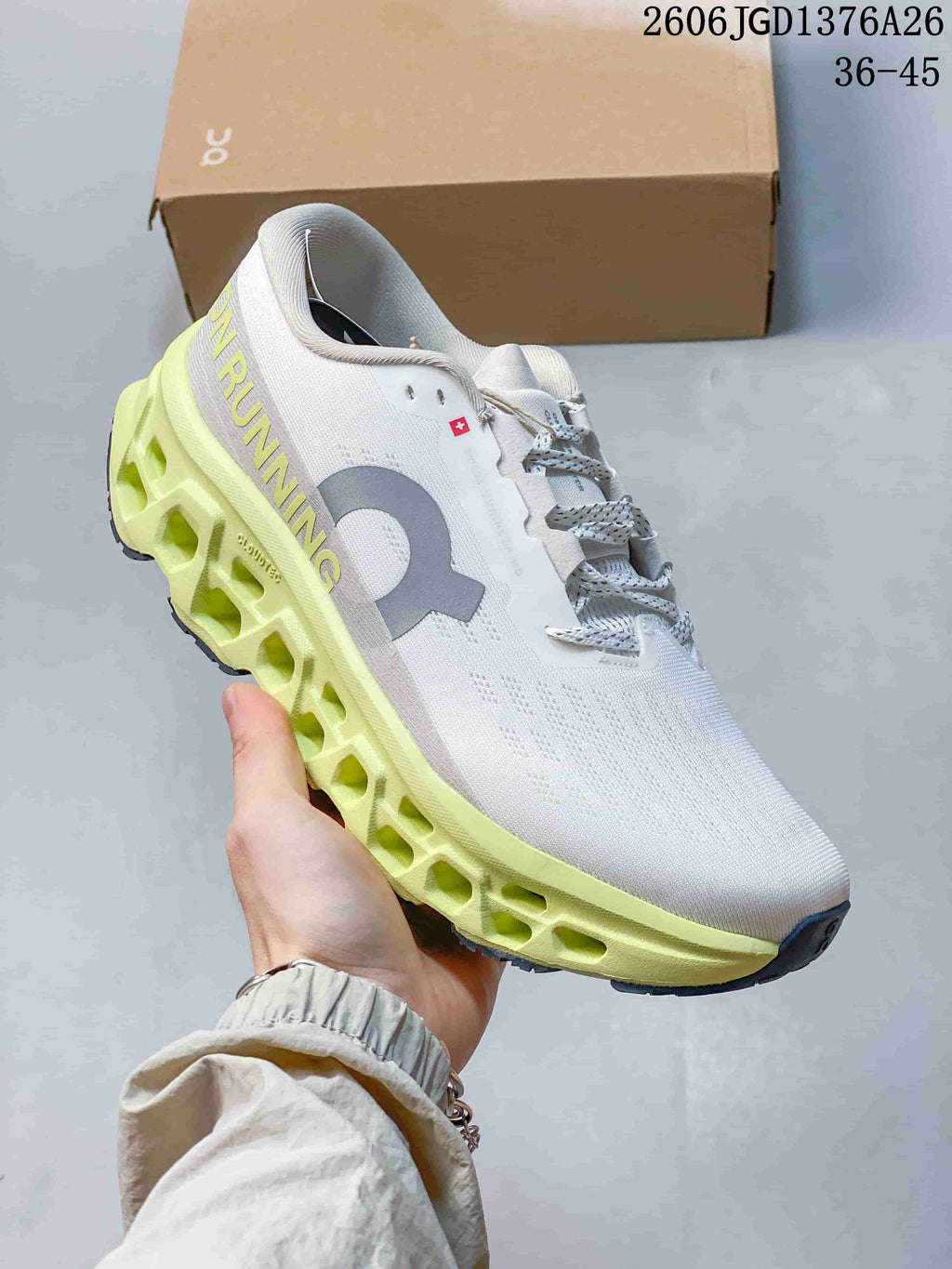 Angled side view of the white and lime On Cloudmonster 3 shoe showing the large side logo, lace closure and segmented midsole.